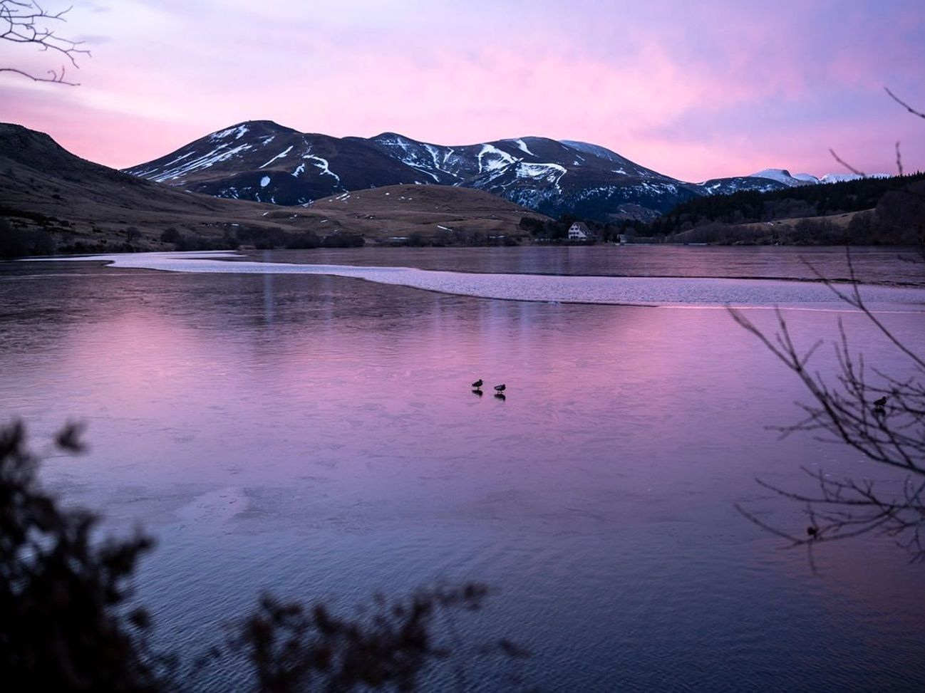 Vista de un lago de montaña cubierto de hielo grueso al amanecer
